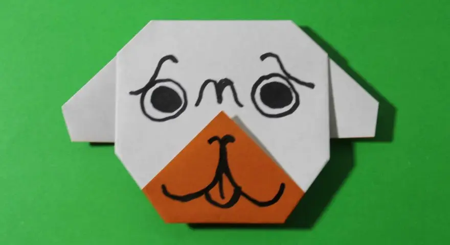Urocza praca plastyczna: origami przedstawiające pyszczek psa z czarnymi oczami i pomarańczowym noskiem.
