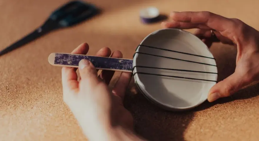 Ręce składają proste instrumenty muzyczne do zrobienia: miseczkę z gumkami i patyczek.