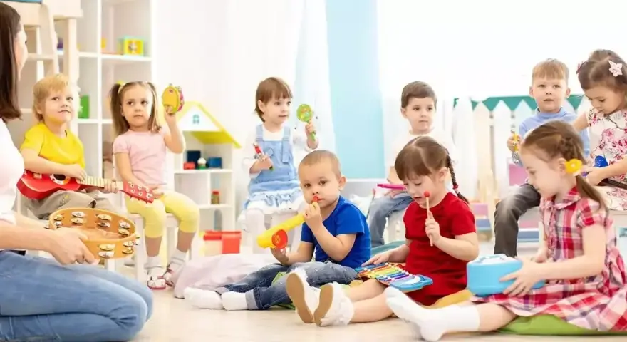Wesołe zabawy w przedszkolu: dzieci grają na instrumentach, śpiewają i bawią się z nauczycielem.