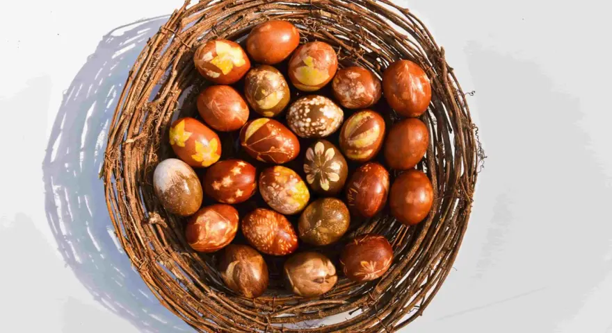 Wielkanocne pisanki w koszyku z gałęzi, barwione w łuskach cebuli, z naturalnymi wzorami liści i kwiatów.