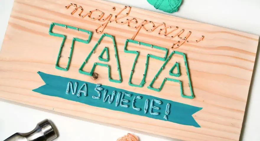 Własnoręczny prezent dla taty od dziecka: napis "Najlepszy TATA na świecie!" wykonany sznurkiem na desce.
