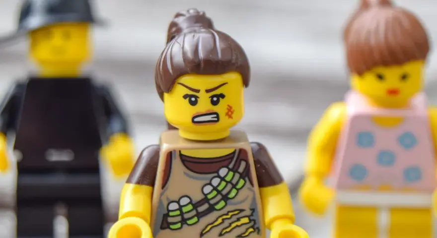 Trzy ludziki Lego. Jeden z nich, w brązowym stroju, ma zaciętą minę, co sugeruje nieradzenie sobie z emocjami.