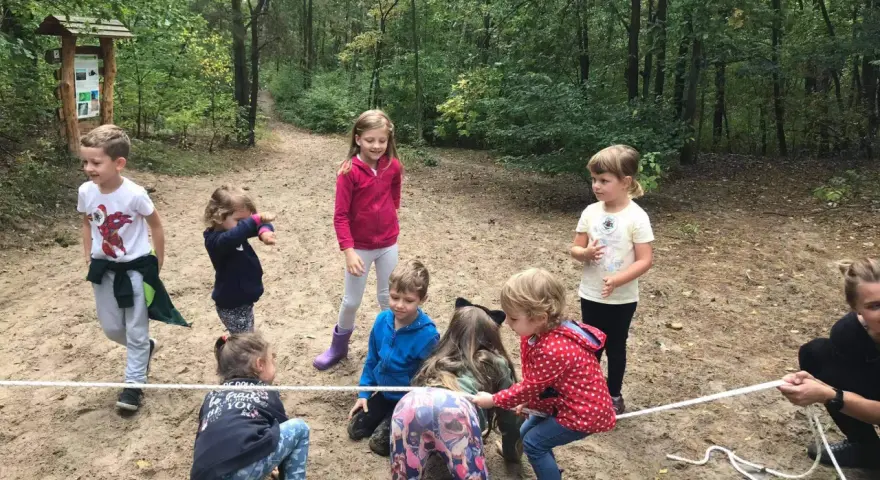 Dzieci biorą udział w leśnej grze terenowej, przeciągając linę.