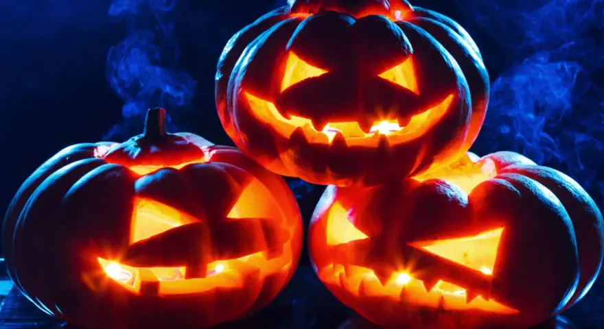 Trzy świecące **jack o lantern** z wyciętymi strasznymi minami, otoczone niebieską mgłą, tworzą mroczny, halloweenowy nastrój.