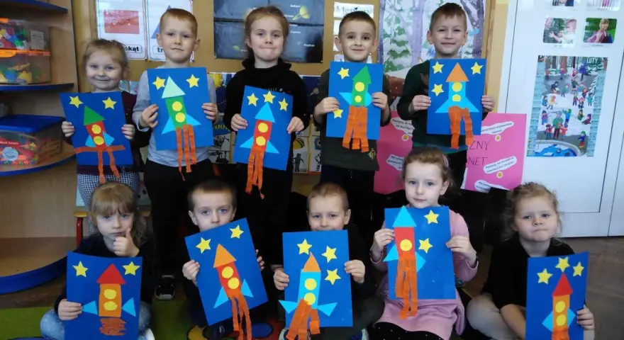 Dzieci prezentują rakiety z figur geometrycznych, gotowe do kosmicznej podróży.