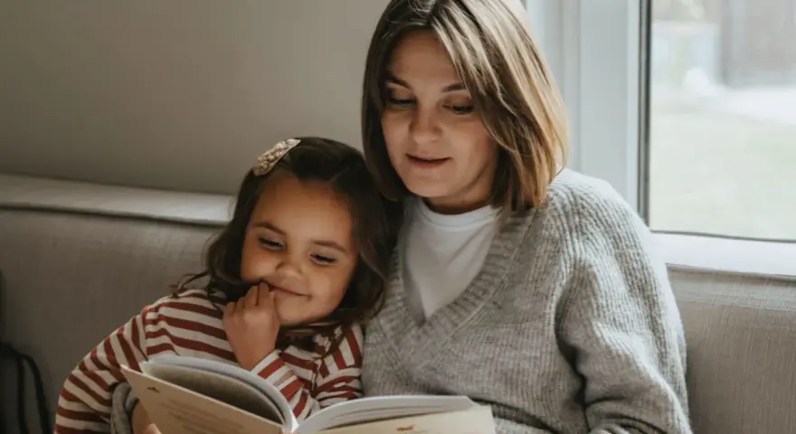 Mama czyta dziecku bajkę, pokazując, jak zachęcić dziecko do czytania. Wspólne chwile z książką budują więź i rozwijają wyobraźnię.