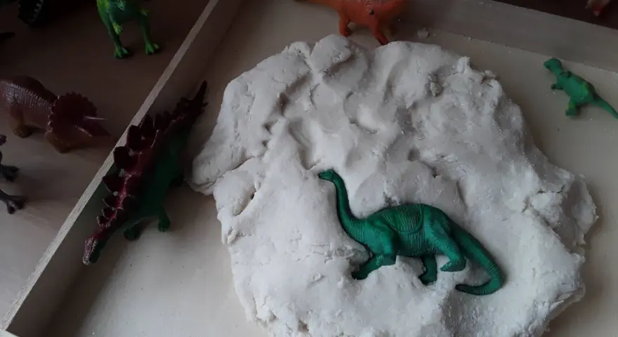 Zabawy z masą plastyczną i figurkami dinozaurów to świetne pomysły na dzień dinozaura. Dzieci mogą tworzyć prehistoryczne krajobrazy.