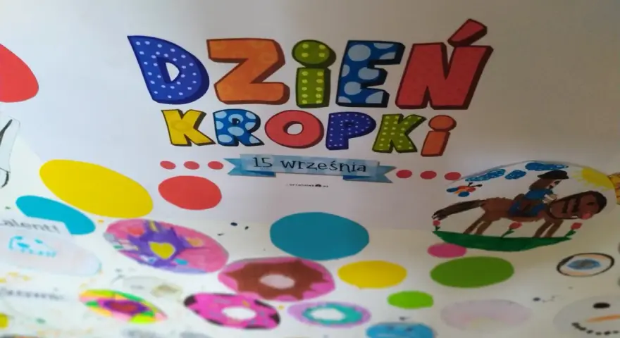 Kolorowa praca plastyczna na Dzień Kropki. Litery "Dzień Kropki" ozdobione kropkami, poniżej rysunki dzieci: konik z jeźdźcem, bałwanek i kolorowe kropki.