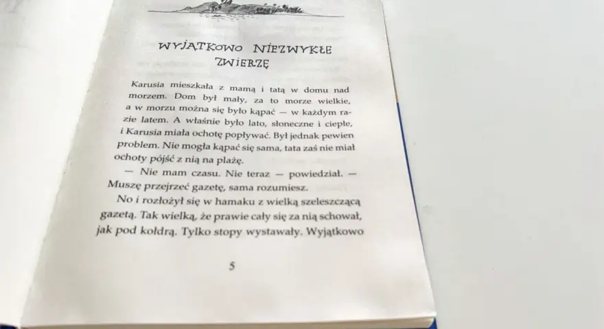 Piaskowy wilk bohaterowie: Karusia i tata nad morzem. Tata czyta gazetę, a Karusia chce popływać.