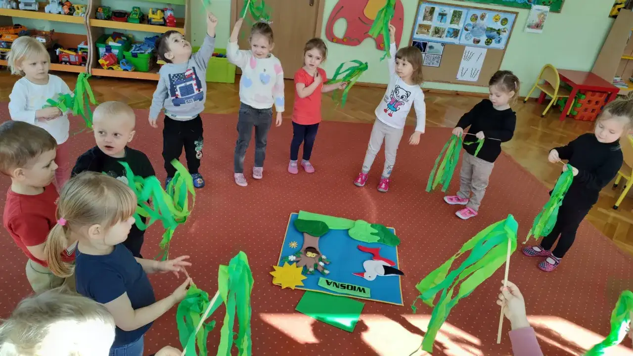 Dzieci w przedszkolu świętują pierwszy dzień wiosny pomysły na zabawy z zielonymi wstążkami.
