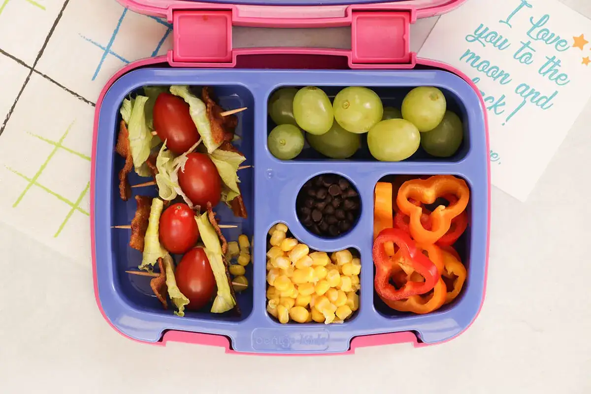 Kolorowy lunchbox z szaszłykami z pomidorków i boczku, winogronami, fasolką, kukurydzą i papryką. Idealne zdrowe śniadanie do szkoły!