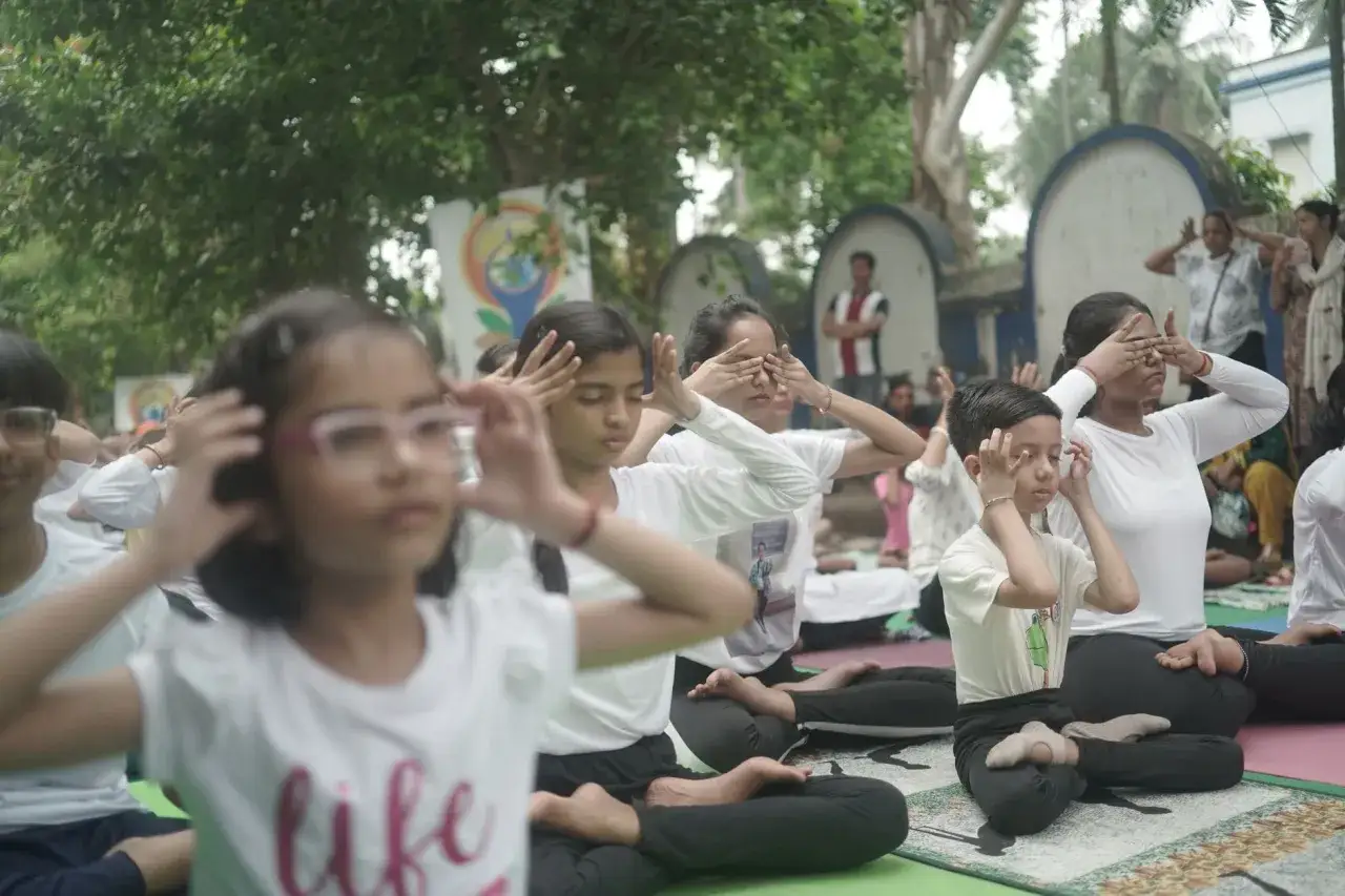Dzieci ćwiczą mindfulness na macie, zamykając oczy i skupiając się na oddechu.