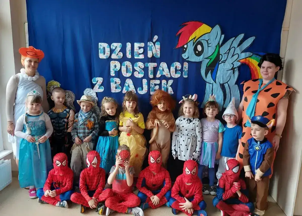 Dzień postaci z bajek w przedszkolu. Dzieci przebrane za Spidermana, Elzę, Króla Lwa i inne bajkowe postacie pozują do zdjęcia.