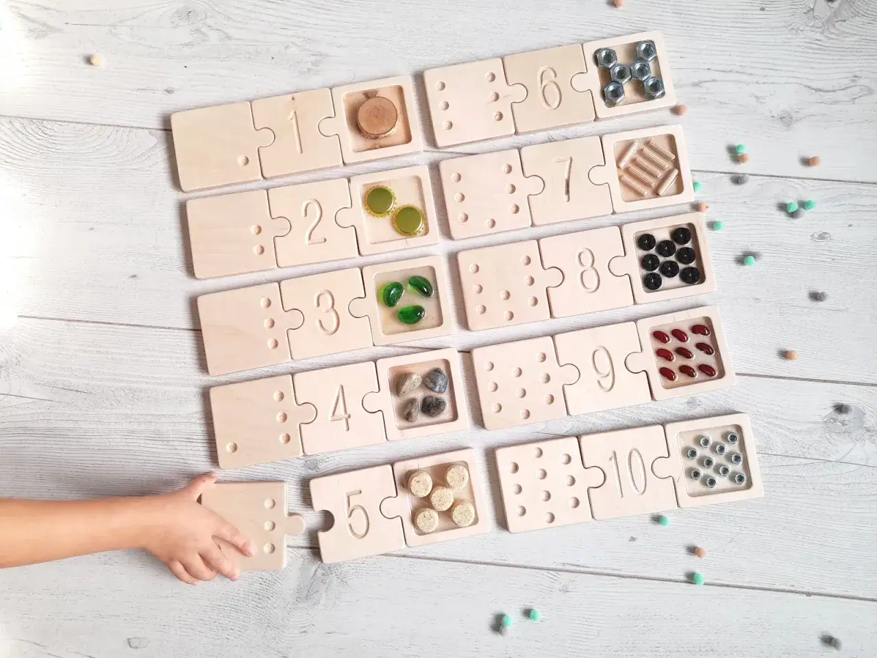 Drewniane klocki z cyframi i miejscem na liczmany. Dziecko układa puzzle z cyframi 1-10, ucząc się liczyć.