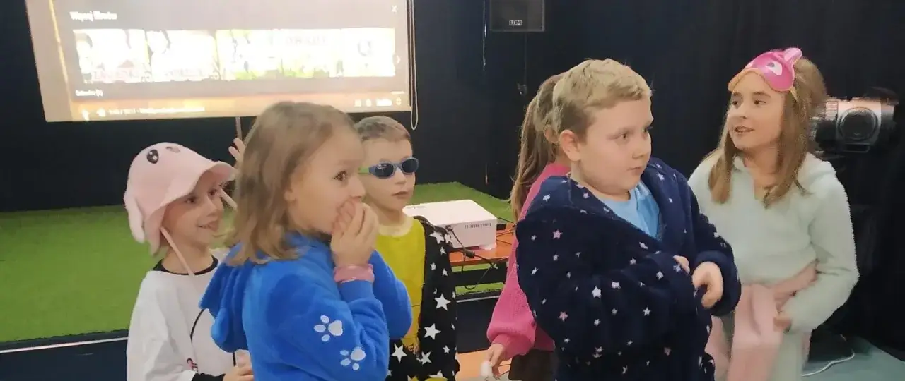 Dzieci w piżamach oglądają bajki na ekranie. Świetne pomysły na andrzejki w szkole!