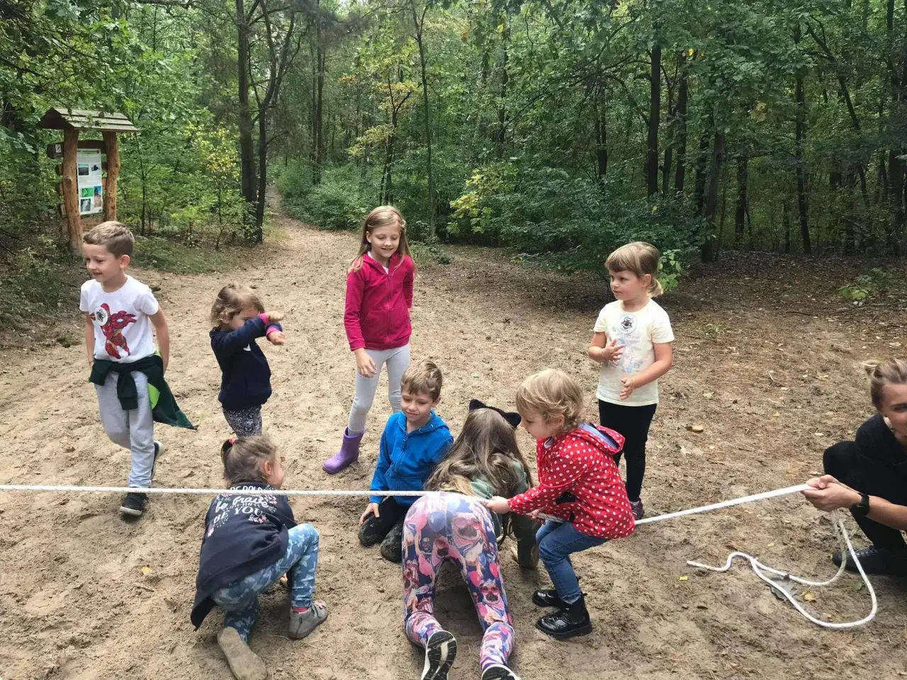Dzieci biorą udział w emocjonującej grze terenowej dla dzieci w lesie, ciągnąc linę.