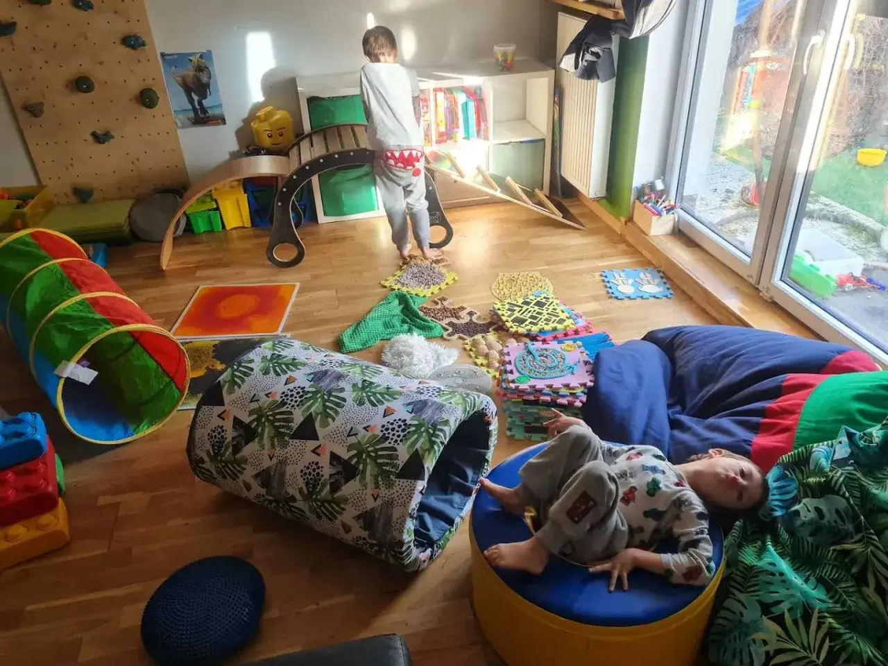Kolorowy pokój pełen zabawek i akcesoriów do zabawy dla dzieci w domu. Dzieci bawią się na podłodze, w tunelu i na miękkich poduchach.