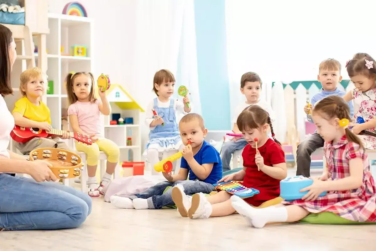 Wesołe zabawy w kole przedszkole: dzieci grają na instrumentach, śpiewają i bawią się z nauczycielem.