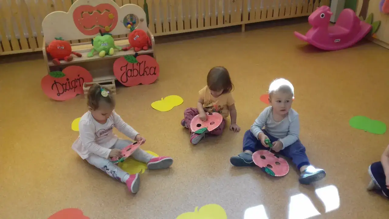 Dzieci w przedszkolu świętują dzień jabłka, tworząc własne, kolorowe jabłuszka z papieru.