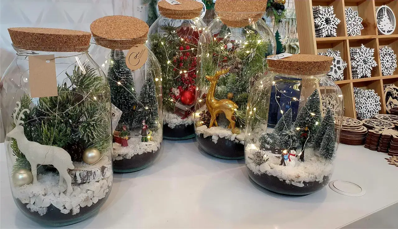 Świąteczne pomysły na ozdoby bożonarodzeniowe ręcznie robione: miniaturowe zimowe scenki w słoikach, oświetlone lampkami.