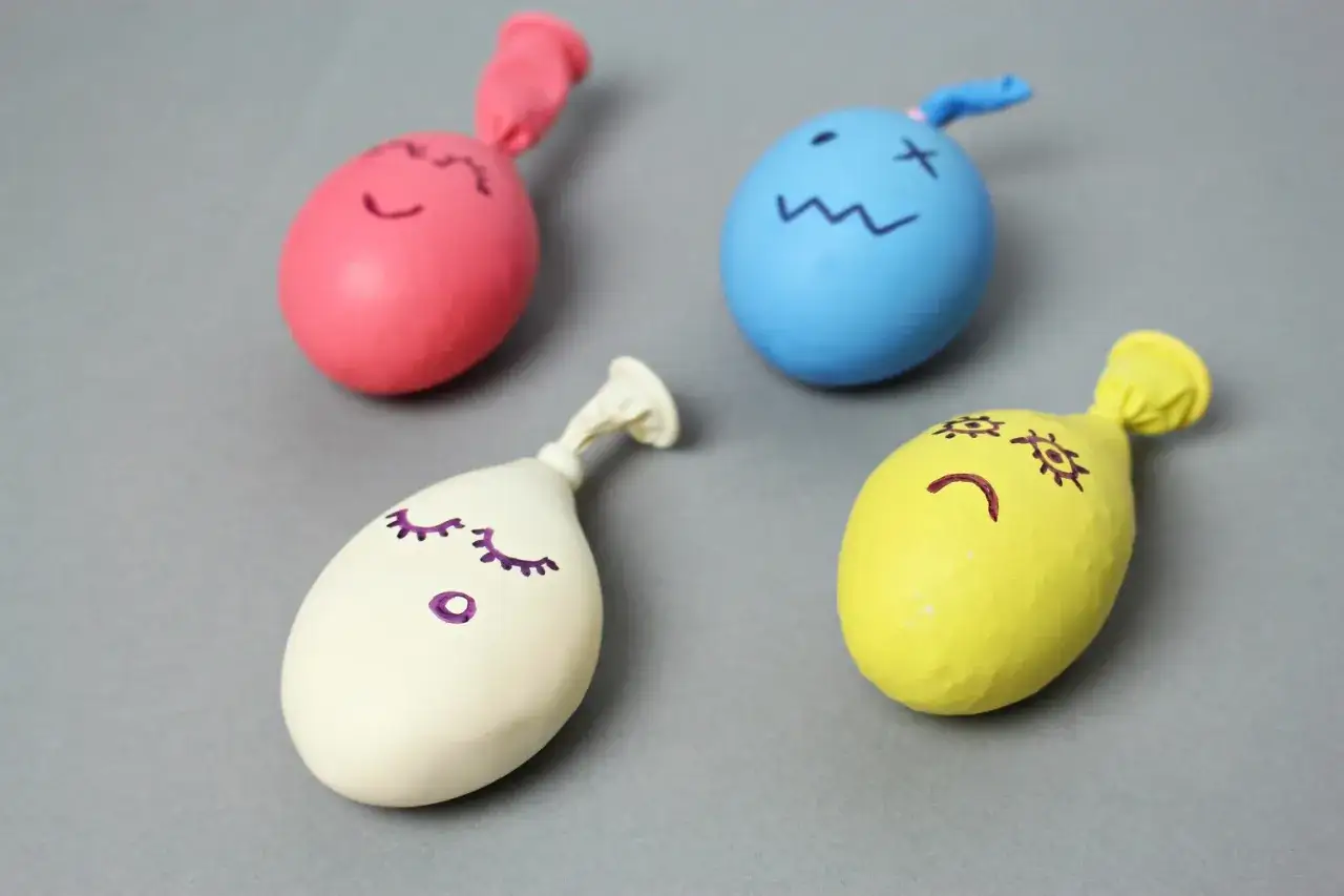 Cztery kolorowe balony z narysowanymi buźkami, gotowe do zabawy. Dowiedz się, jak zrobić gniotka!